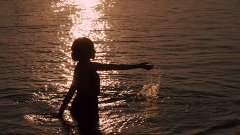 Silhouette-Einer-Frau,-Die-Während-Der-Goldenen-Stunde-Des-Sonnenuntergangs-Wasser-Im-Meer-Spielt