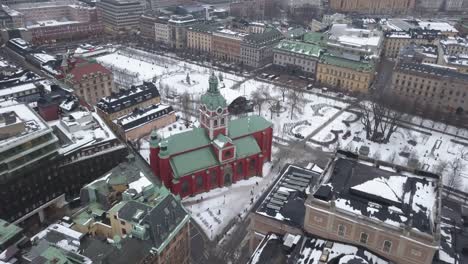 Imágenes-Aéreas-Que-Se-Acercan-A-La-Vibrante-Iglesia-Roja-Y-Verde-En-El-Centro-De-Estocolmo,-Suecia