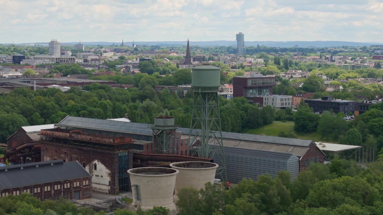 Kredsende droneudsigt over et tidligere stålværk og byen Bochum på en overskyet dag