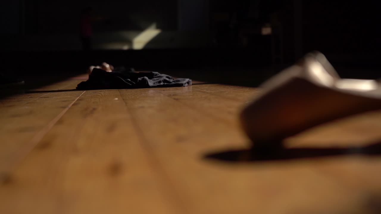 en una habitación oscura y vacía, un traje de ballet cae en cámara lenta.