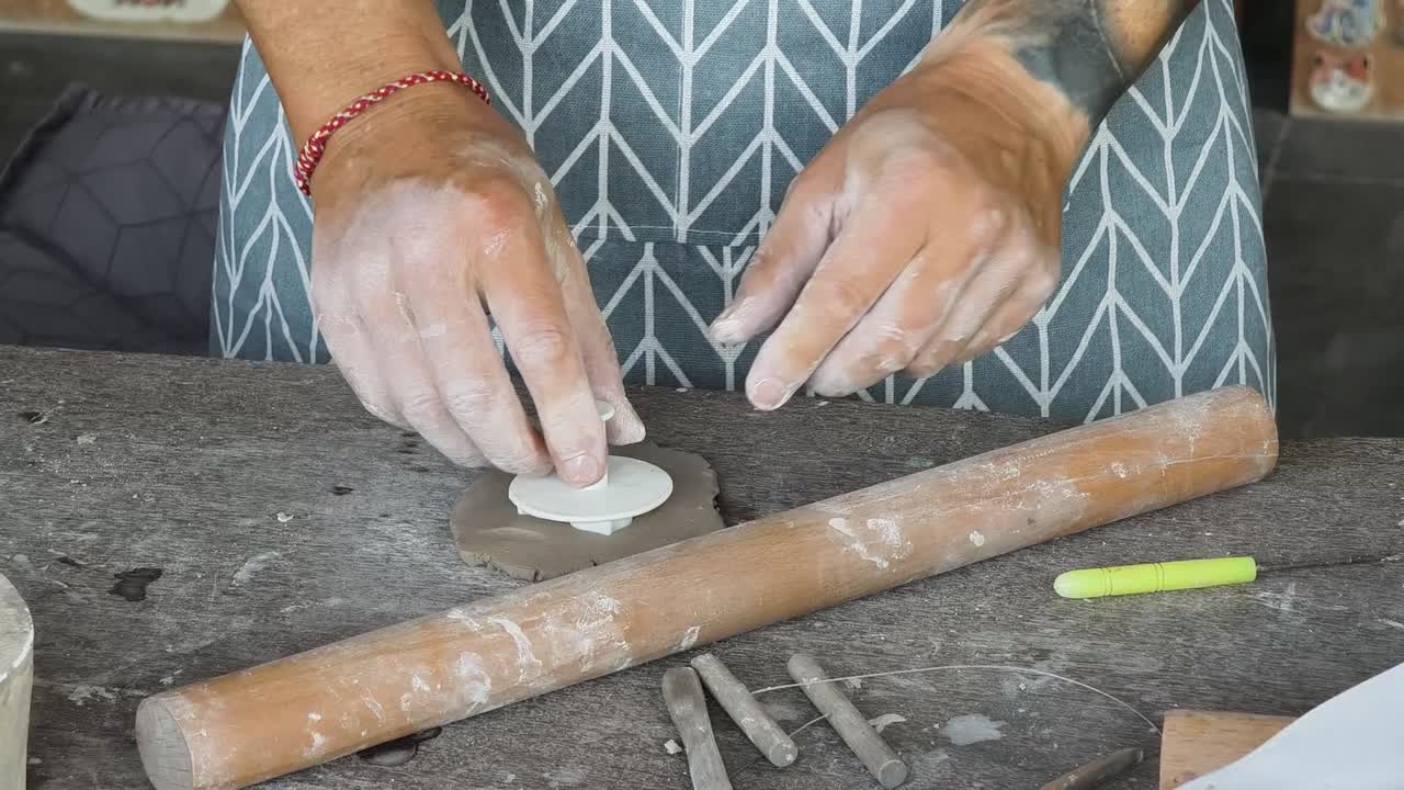 Primo piano di mani che modellano l'argilla con un mattarello e un taglierino