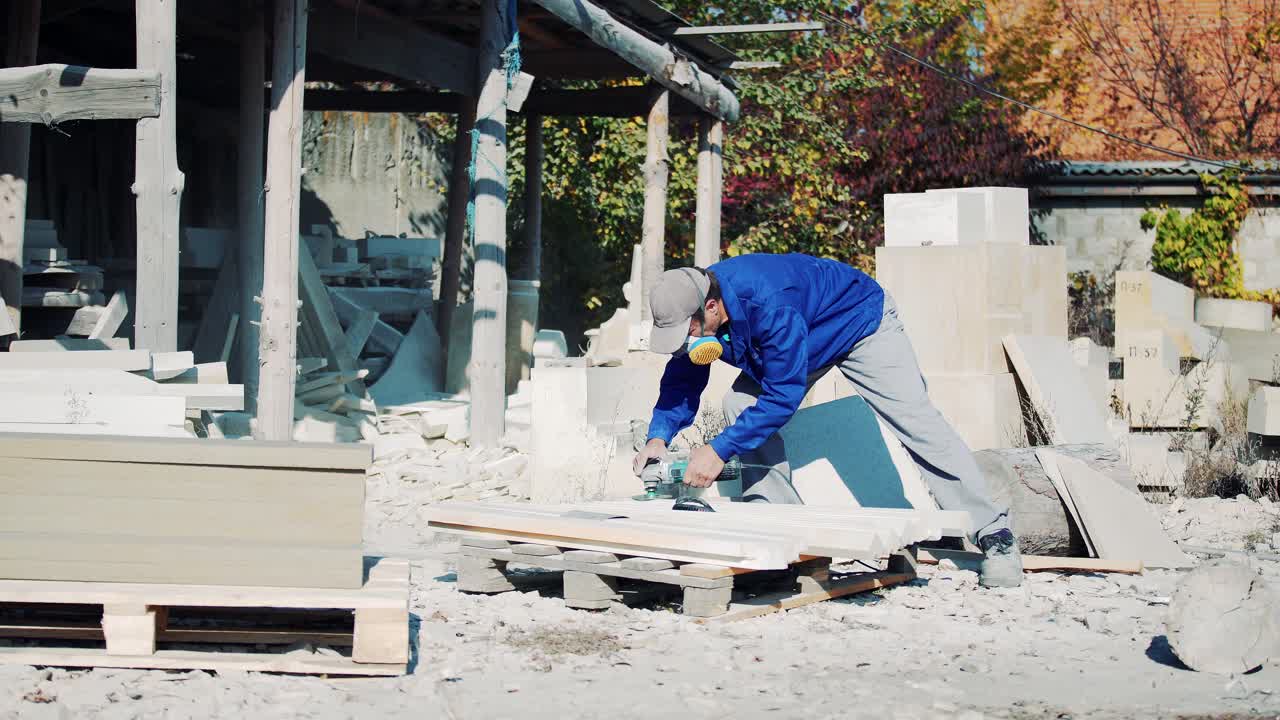 A man in a respirator polishes a stone with an electric angle grinder. Sandstone art processing factory