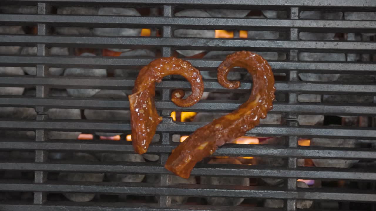 Fresh octopus sizzles on a grill, with flames