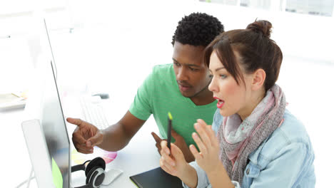 Attractive creative designer talking to her colleague sitting at the desk