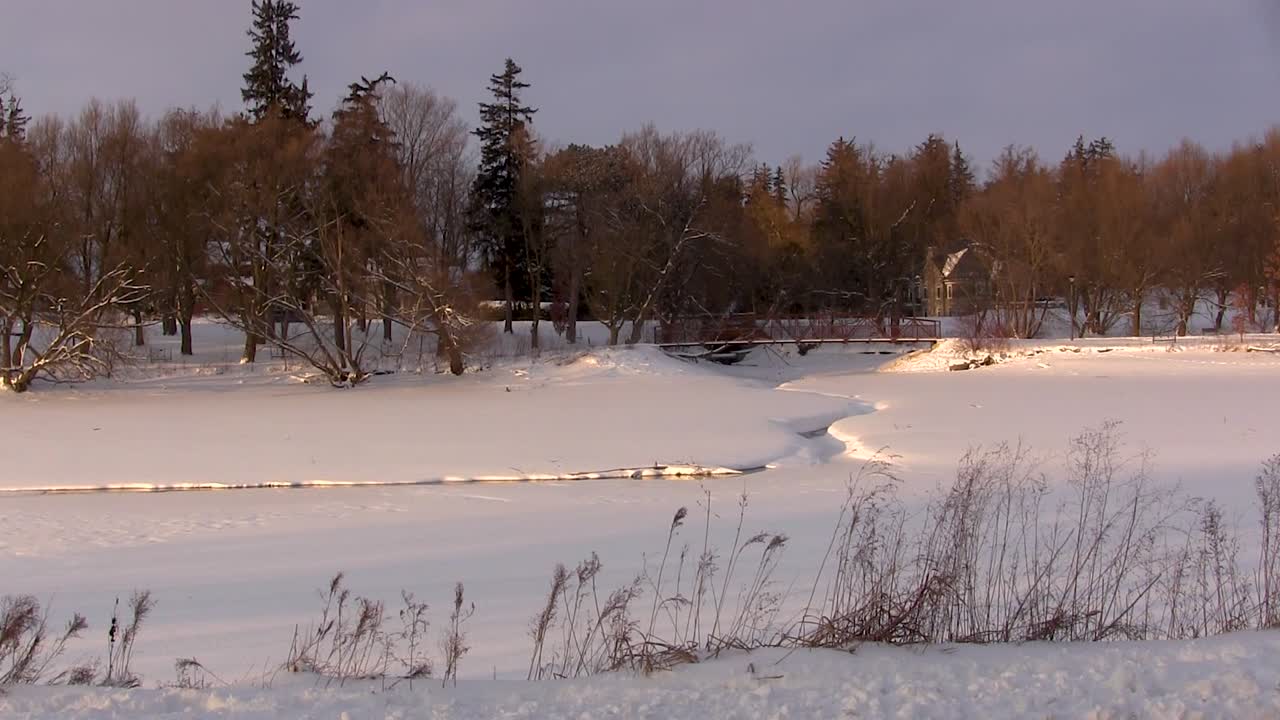 ручей протекает под мостом и по покрытому снегом полю