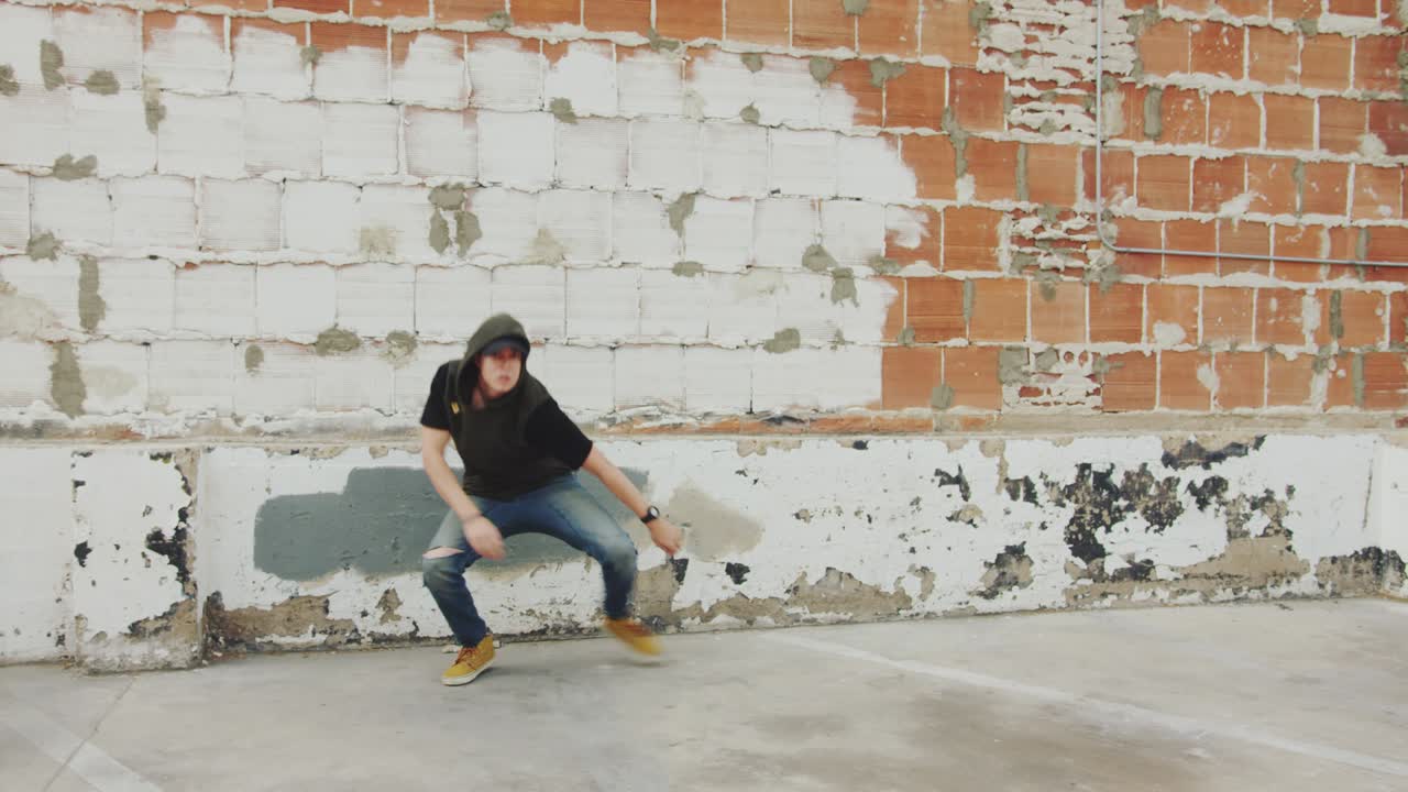hombre de hip hop bailando afuera en la ciudad frente a una pared de ladrillo