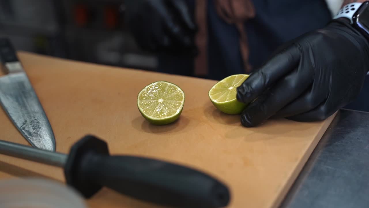 A professional chef cuts a lime with a sharp knife and walks away form the cutting board