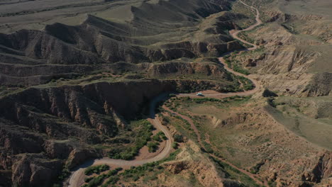 Pintoresca-Vista-Aérea-De-Un-Automóvil-Que-Viaja-A-Lo-Largo-De-Un-Camino-Sinuoso-A-Través-Del-Cañón-De-Cuento-De-Hadas-En-Kirguistán