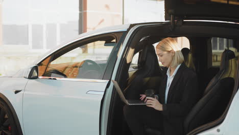 businesswoman working on laptop in electric suv
