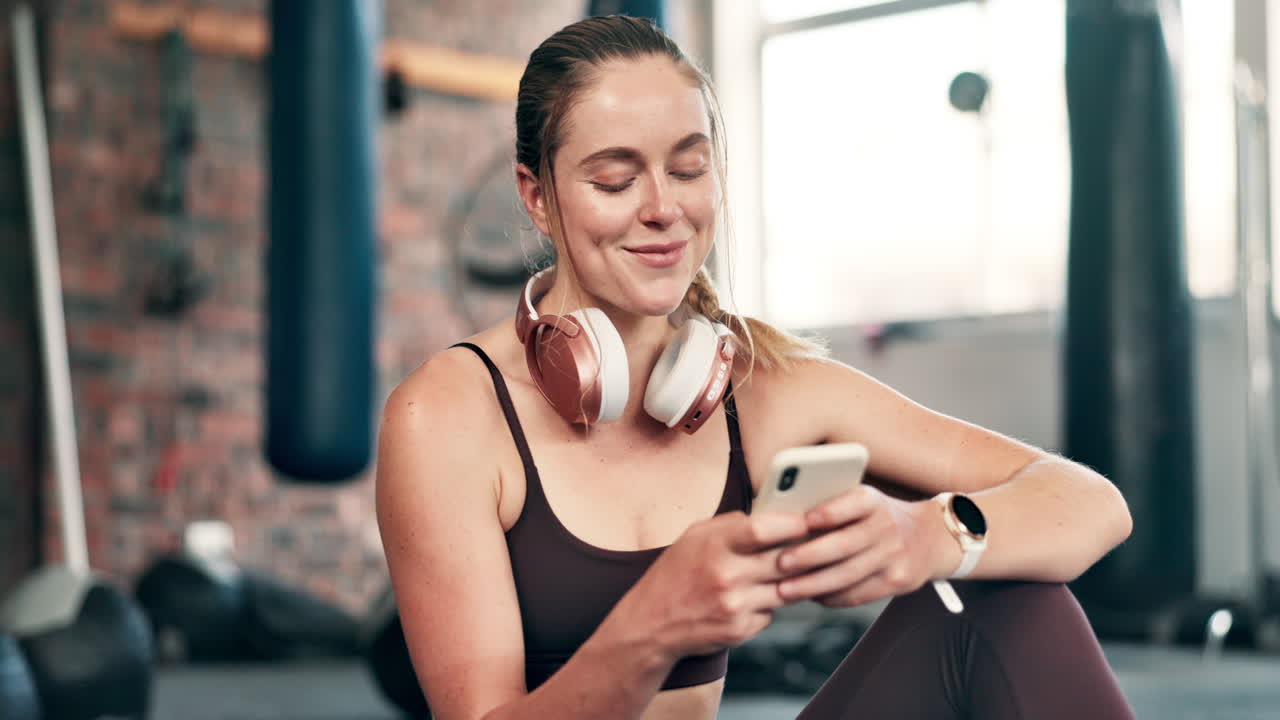mujer relajándose con un teléfono en el gimnasio