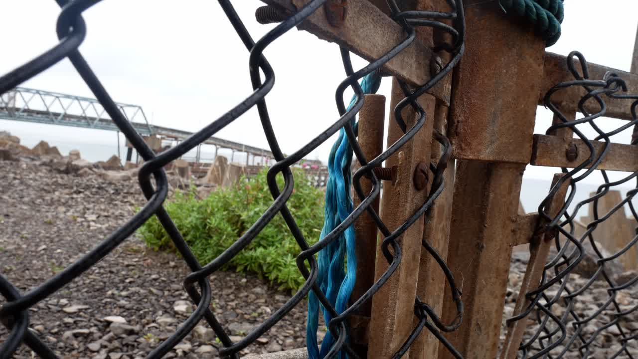 건설 엔지니어링 현장에서 녹슨 게이트 체인 링크 워터프론트 보안 울타리를 확보하고 돌리 오른쪽을 닫습니다.