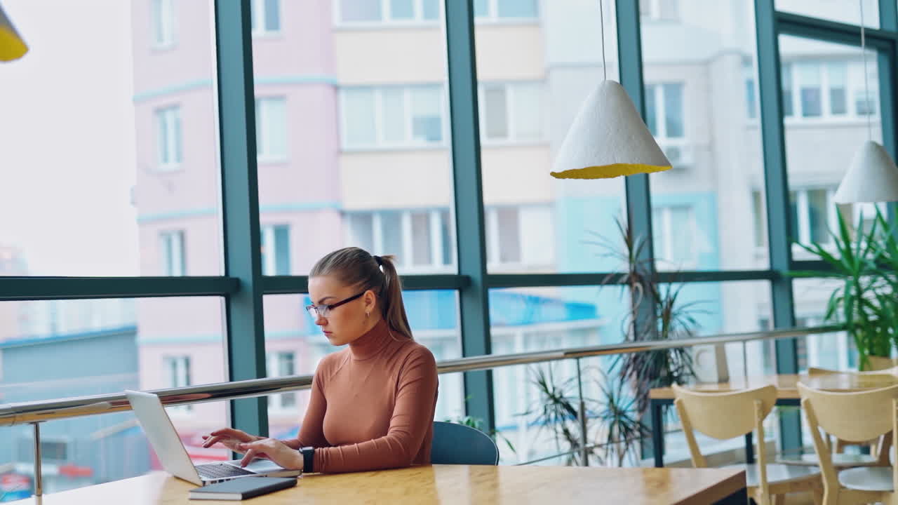 Focused woman etrepreneur typing on laptop. Young female using computer while sitting at home desk. Busy worker freelancer working on modern device.