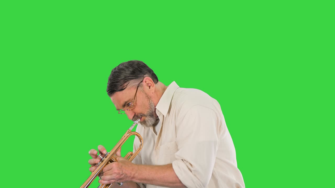 Anziano con gli occhiali che suona la tromba su uno schermo verde, Chroma Key.