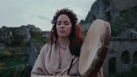 spiritual woman playing a shamanic drum in a beautiful medieval village gimbal slow motion medium shot