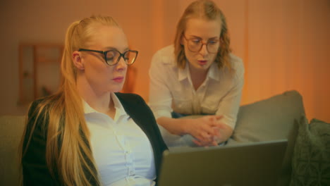 two friends work on laptop late at night discussing startup ideas