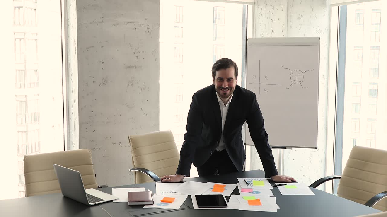 joven confiado de 35 años, hombre de negocios en traje formal, posa en el lugar de trabajo