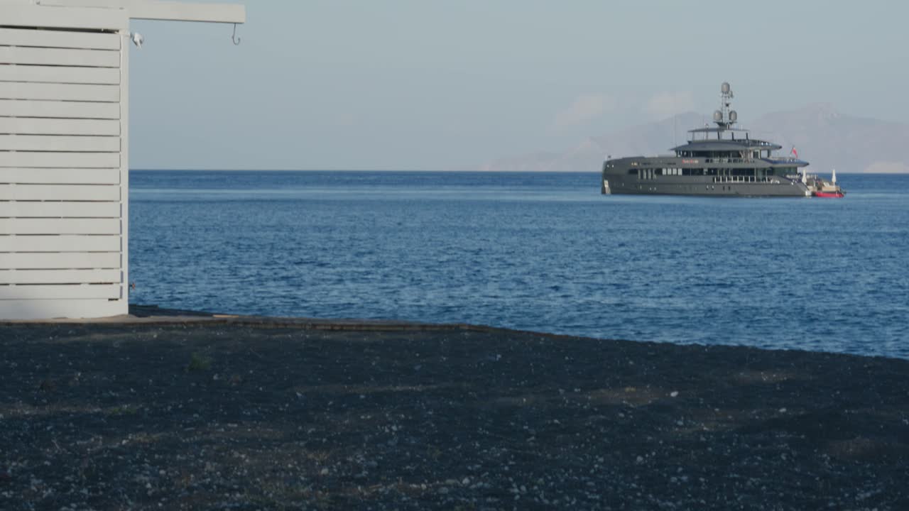 Mega yacht close to beachside in ocean in Santorini, Greece