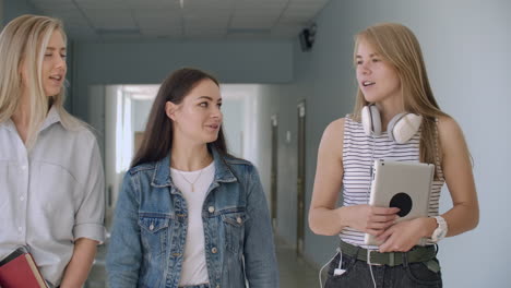 University-corridors-three-girls-go-along-the-corridor-and-laugh-cheerfully-and-talk-about-school-and-guys.-College-Institute-and-Communication