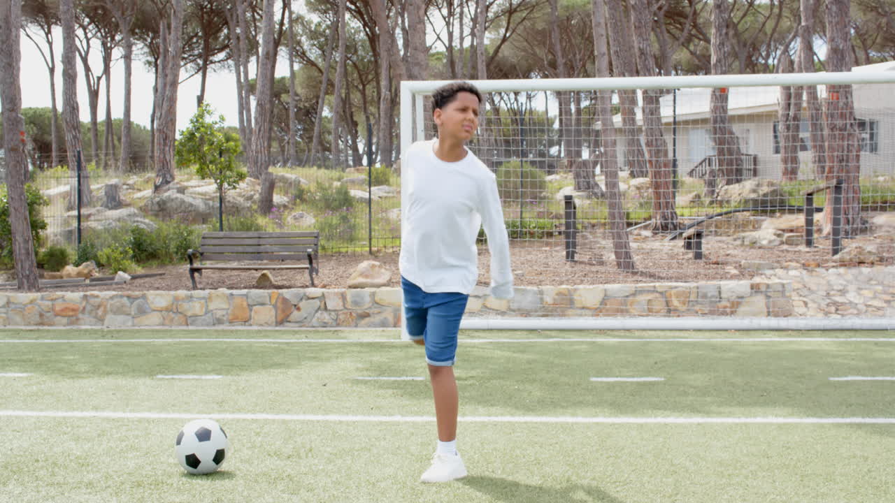 Boy standing on soccer field with ball, looking focused and determined, copy space