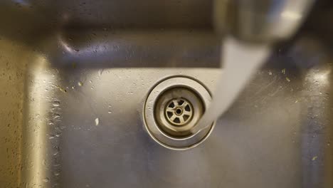 water running into a stainless steel kitchen sink