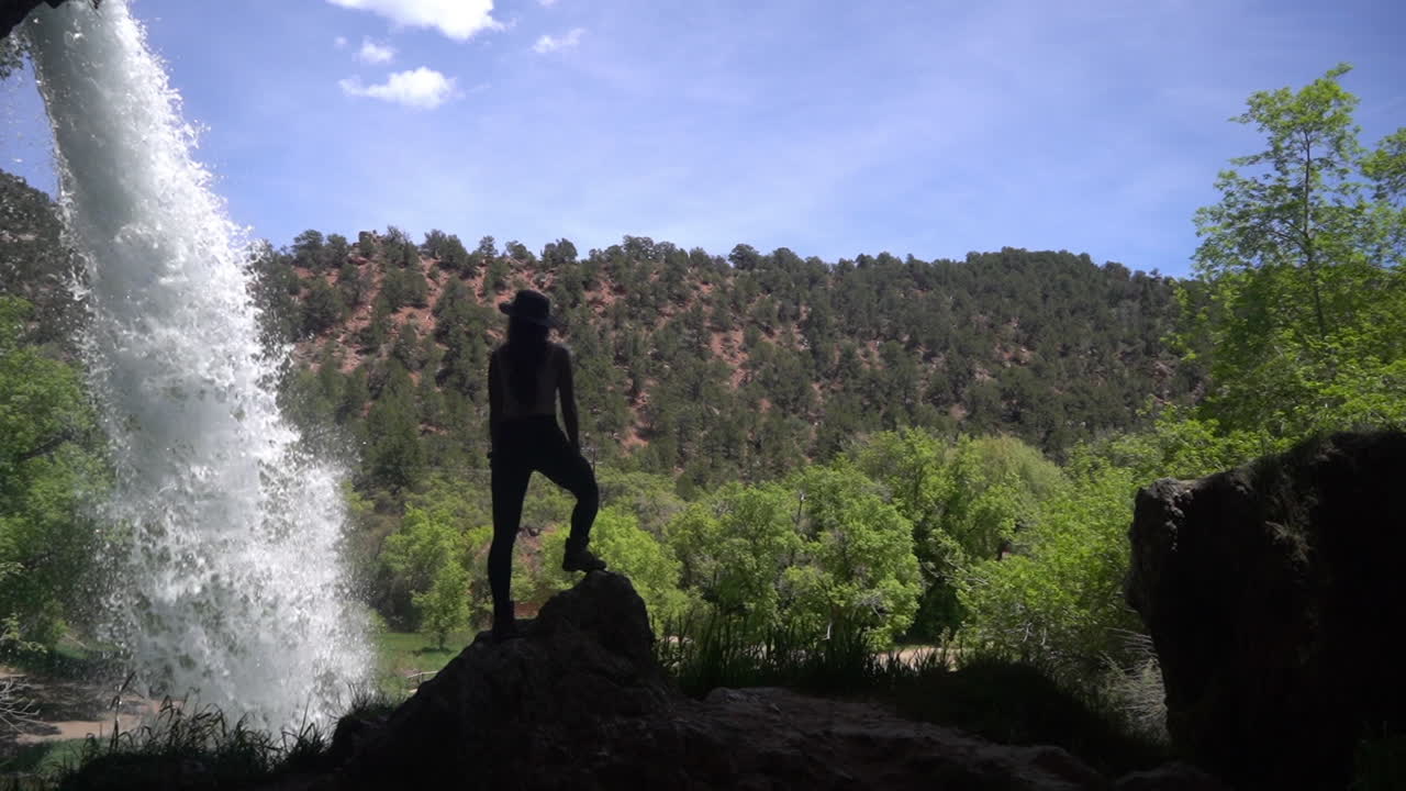 exploradora de pie sobre una roca bajo cascadas escénicas