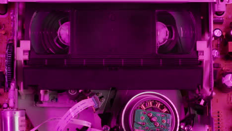 vhs player, old video recorder inside in neon pink light close-up, vhs. retro player in neon blue light, vintage video cassette broadcasting, audio tape.