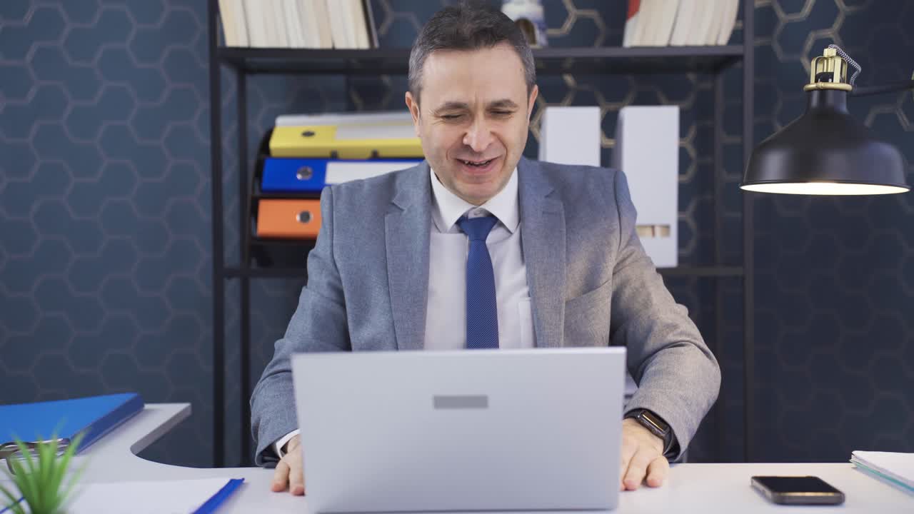 Uomo che lavora al laptop in ufficio, che gioisce per le buone notizie ricevute e raggiunge i suoi obiettivi.