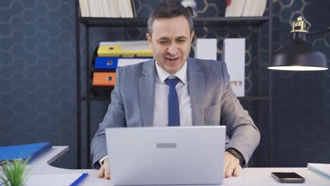 hombre trabajando en la computadora portátil en la oficina, regocijándose en las buenas noticias que recibe, logra sus metas.