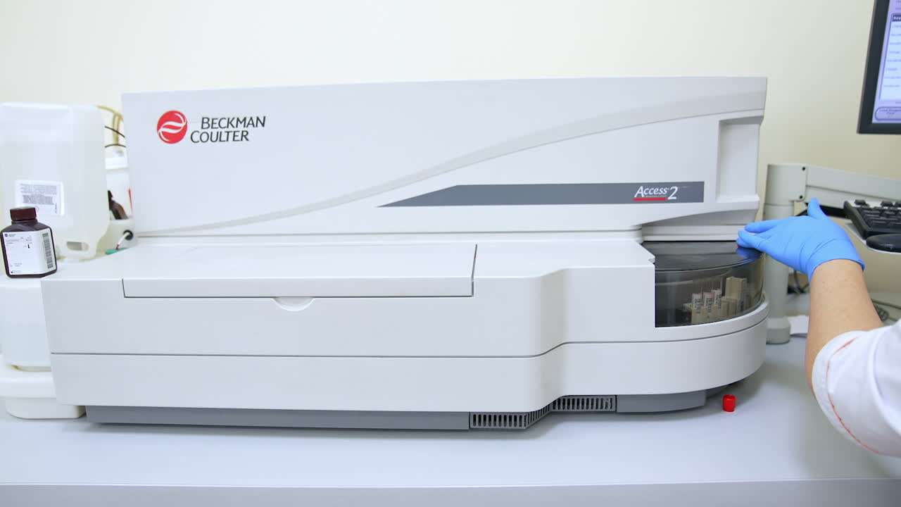 Female hand in the blue latex gloves closing the lid at apparatus. Scientist working in the blood test laboratory in modern clinics.