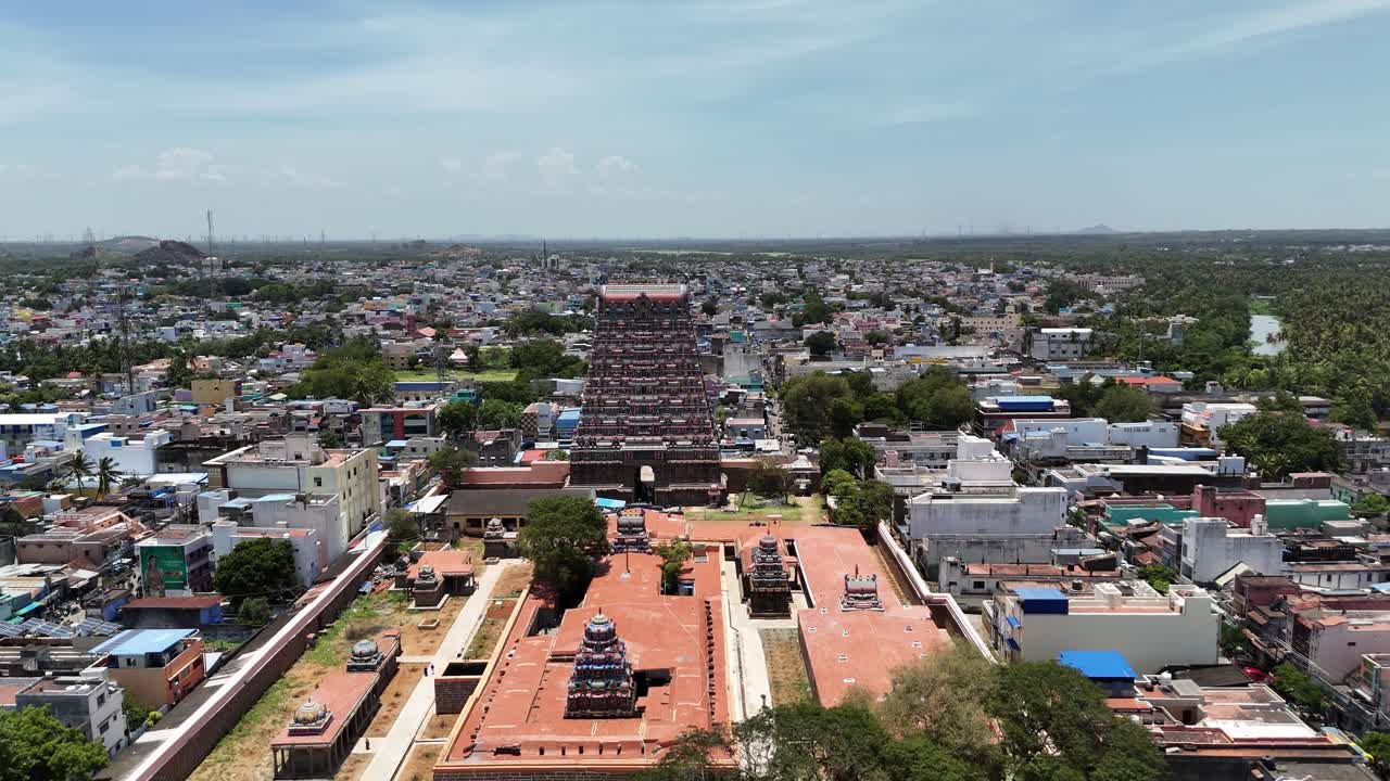 Aerial close-up of the Kasi Viswanathar Temple in Tenkasi, Tamil Nadu, with its towering gopuram surrounded by colorful town buildings and hills in the distance under a bright sky