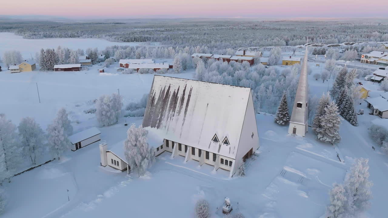 Aerial rising shot tilting in front of the Salla church, winter sunset in Finland
