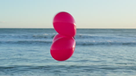 three red balloons pass by the out of focus sea view