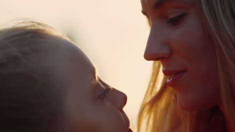 Woman-kissing-girl-in-city-park.-Daughter-licking-mother-nose-outdoor.