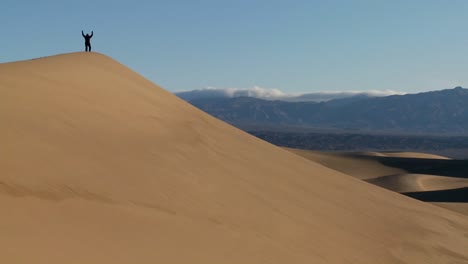 A-person-jumps-up-and-down-on-a-desert-dune-to-symbolize-victory-or-achievement-of-a-goal