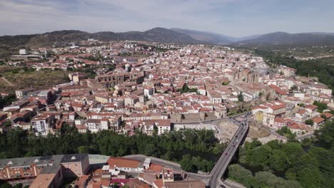 Majestic-aerial-view-of-hilltop-city,-mountain-backdrop