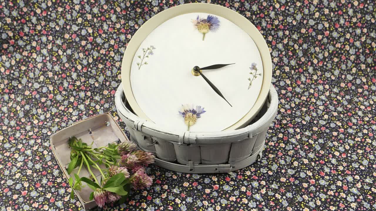 A clock and flowers are on the  fabric with a floral pattern, floristic composition