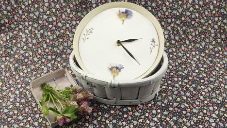 a clock and flowers are on the  fabric with a floral pattern, floristic composition