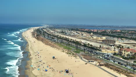 Drone-flying-in-Huntington-Beach-California-looking-at-the-traffic-on-PCH-and-some-large-waves-breaking-on-the-shore