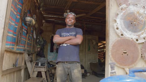 Trabajador-Negro-Africano-Sonríe-Al-Alejar-La-Cámara-En-Su-Lugar-De-Trabajo-En-Ghana,-África