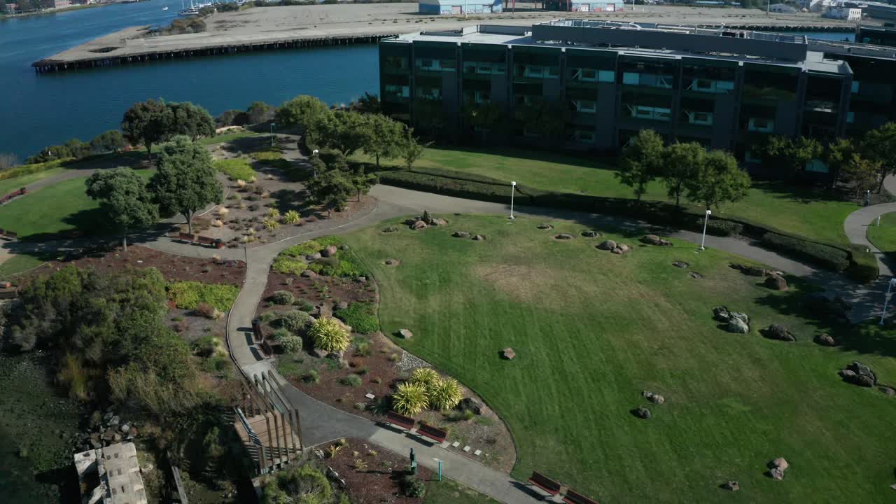 A large business center with a park and walkway along the shore on a sunny day