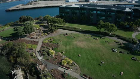 a large business center with a park and walkway along the shore on a sunny day