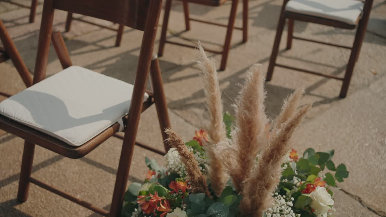 Elegante montaje para ceremonia de boda al aire libre con sillas de madera y flores