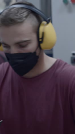 man in face mask and ear protection working in industrial setting