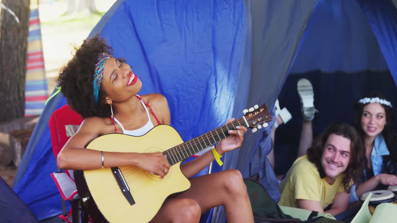 Woman playing guitar for her friends at a music festival 4k