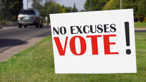 Political-Voter-Rally-Sign-Next-to-Road-with-Cars-Driving-By-Close-Up,-No-Excuses-Vote