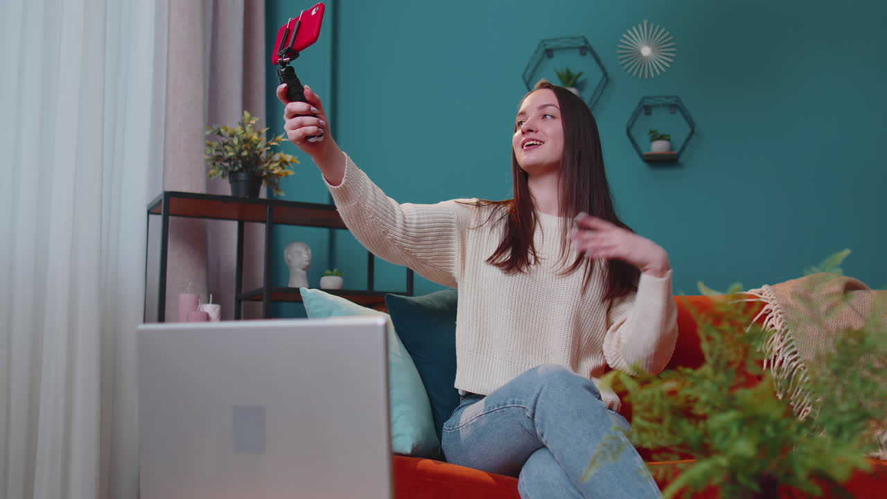 Giovane blogger e influencer si scatta un selfie con lo smartphone, creando contenuti video online per i social media a casa.