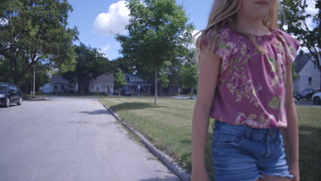 young blonde girl walking past camera on way to school