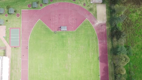 vista aérea de arriba hacia abajo de una pista de atletismo vacía en un campo verde