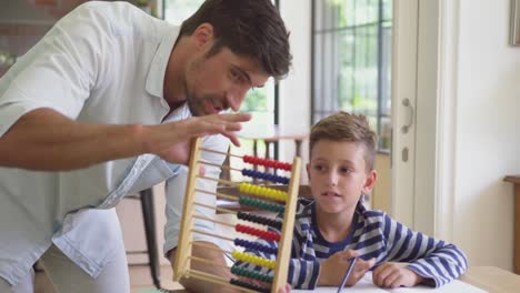 Vater-Bringt-Seinem-Sohn-Mathematik-Am-Tisch-In-Einem-Komfortablen-Zuhause-Bei-4k