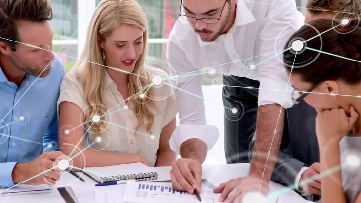 Standing man pointing at chart, starting network overlay growing over papers while biz team noting